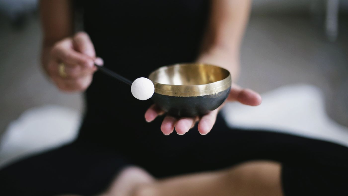 woman in yoga attire with singing bowl